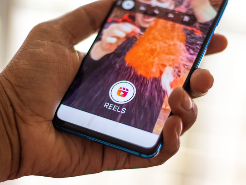 A cell phone shows the Instagram Reels splash screen